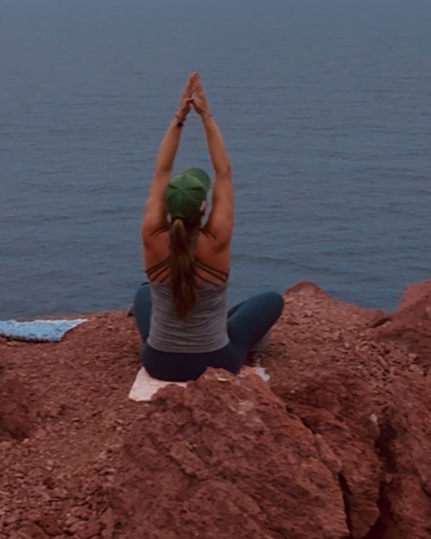 Patricia practicing yoga on the rocks above the ocean